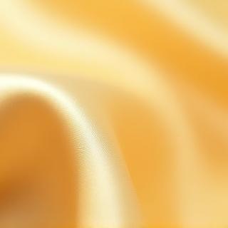 Close-up of a luxurious silk fabric swatch in soft gold, indicating premium bedding material